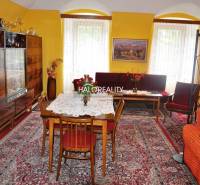 Living room in a family house with a carpet, display cabinet, and floral decoration.