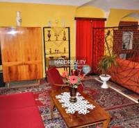 Interior of a family house with retro furniture, red curtains, and a carpet with an oriental pattern.