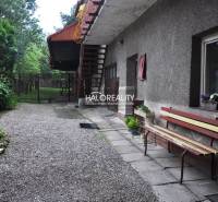 The courtyard of a family house in Nálepkovo with a bench and a garden full of greenery.