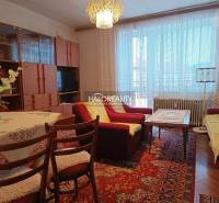 Living room in a two-room apartment with a sofa, carpet, and a display cabinet with a wooden decor.
