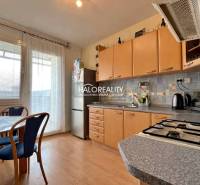 A kitchen in a 3-room apartment with a wooden decor floor and light furniture.