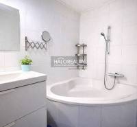 Bathroom with a corner bathtub and a mirror in a 4-room apartment, white tiles.