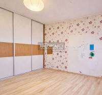 A room in a 4-room apartment with a floor featuring a wood decor and wallpaper with a floral pattern.