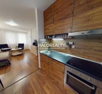 A kitchen with a wooden decor floor, connected to the living room in a 3-room apartment.