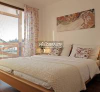 A bright bedroom in a 3-room apartment, with a bed and a wooden-patterned floor.