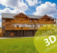 A wooden building in Demänovská Dolina with a blue sky and green grass.