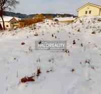 A snowy residential plot in Liptovské Beharovce, with a view of the surrounding hills and houses.