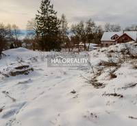 Snow-covered residential plots surrounded by nature in Liptovské Beharovce with a view of the hills.