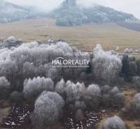 Snow-covered recreational plots in Liptovský Ján surrounded by a winter landscape and deciduous trees.