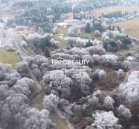 Winter landscape with recreational plots in Liptovský Ján surrounded by snow-covered trees.