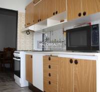 A kitchen in a 2-room apartment with a wooden decor floor and a vintage backsplash.