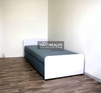 A single bed in a room, wood-patterned floor, white walls.