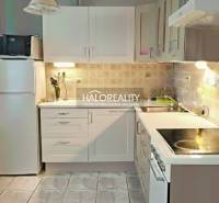 A kitchen in a 3-room apartment with a light-colored kitchen unit, stove, and refrigerator.