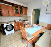 A kitchen in a studio apartment with wooden furniture and ceramic flooring.