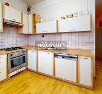 A kitchen in a 3-room apartment with a wood-patterned floor and built-in appliances.