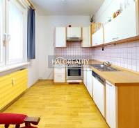 A kitchen in a 3-room apartment with a wooden decor floor and a simple kitchen unit.