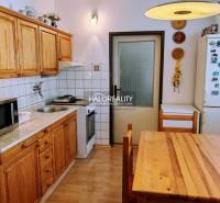 A kitchen in a 3-room apartment with a wooden decor floor and wooden furniture.