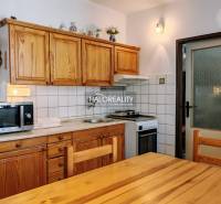 A kitchen in a 3-room apartment with wooden furniture and white tiles above the work surface.