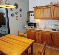Dining room in a 3-room apartment with a kitchen unit and wooden decor furniture.