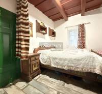 A rustic room in a cottage with a bed, a cabinet, and a wooden decor floor.