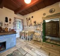 A rustic kitchen in a cottage with a blue stove, decorative plates, and a wooden-patterned floor.