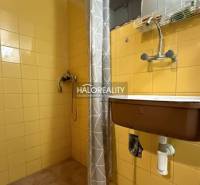 A shower corner in a cabin with bright yellow tiles and a gray curtain.