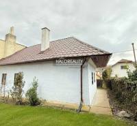 A cottage in Horná Ves with a white facade, a sloped roof, and a well-maintained garden.