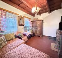 A living room in a cottage with traditional wooden furniture and decorative curtains.