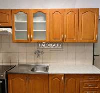 A kitchen with wooden cabinets and a stainless steel sink in a 4-room apartment.