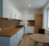 A kitchen with white cabinets and a wood-patterned floor in a two-room apartment.