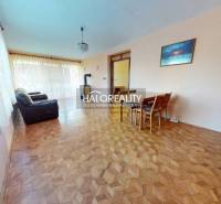 Living room with wood-patterned flooring, a sofa, and a dining table in a family house.