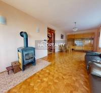 Living room in a family house with a fireplace, sofa, and wood-patterned flooring.