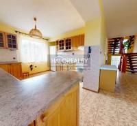 A kitchen in a family house with a living room, staircase, and yellow walls.