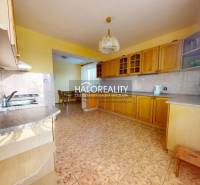 A kitchen with wooden cabinets and ceramic flooring in a family house.