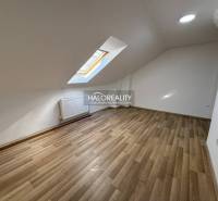 Attic studio with a window, white walls, and a floor with a wooden decor.