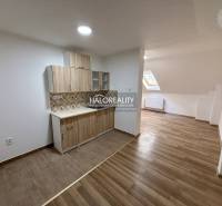 A studio apartment with a wooden floor and a kitchenette.