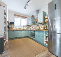 A kitchen in a 3-room apartment with a wooden decor floor, a large refrigerator, and light.