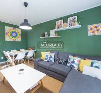 Living room with a sofa, dining table, and wooden decor flooring in a three-room apartment.