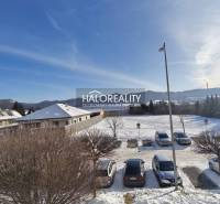 Snowy landscape and cars parked near a building in Žiar nad Hronom.