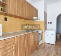 A kitchen in a 3-room apartment with a wooden decor floor and wooden cabinets.