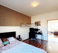 A bedroom in a three-room apartment with a wooden decor floor and a desk.