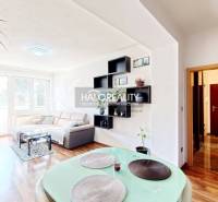 Living room of a three-room apartment with a wooden decor floor and light seating.