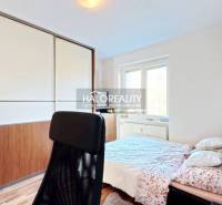 Bedroom with a large wardrobe, wood-decorated flooring, and an office chair in a 3-room apartment.