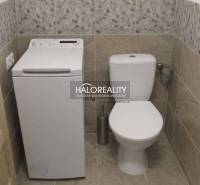 Toilet with a washing machine in the bathroom of a family house, stone-patterned tiles.
