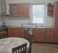 A kitchen in a family house with wooden decor, a dining table, a kitchen unit, a window.
