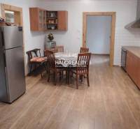 A kitchen in a family house with a dining table and a wooden-patterned floor.