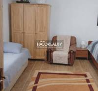 Bedroom in a family house with a wood-patterned floor, beds, and a chair.