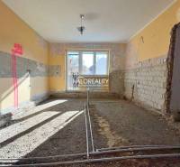 The interior of a family house under renovation with visible brick walls and a window.