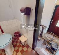 Bathroom in a family house with a toilet, a bucket, and a tiled floor.