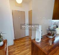 A kitchen of a 2-room apartment with a wooden decor floor and practical accessories.